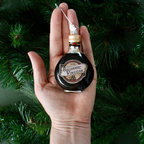 Balsamic vinegar bottle ornament held in a hand with a Christmas tree background