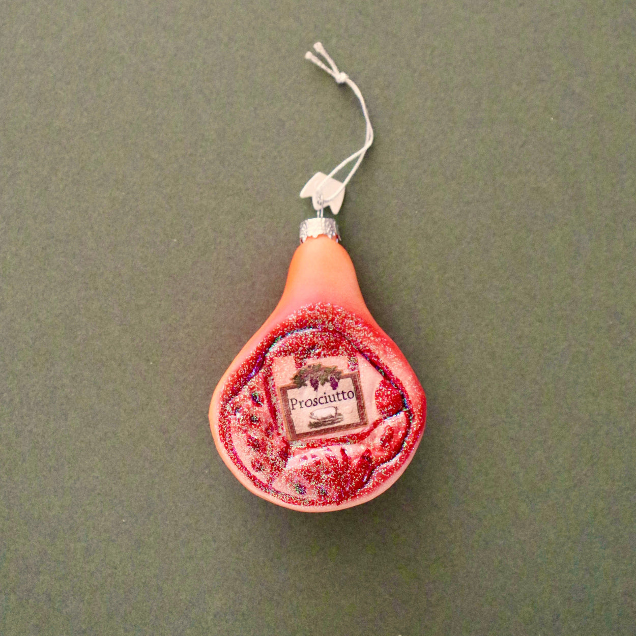 Glass prosciutto ham Christmas ornament on green background
