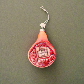 Glass prosciutto ham Christmas ornament on green background