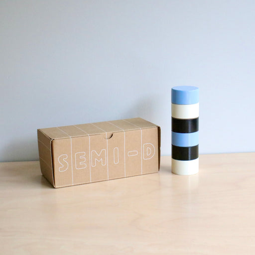 Cardboard box with 'SEMI-D' branding next to a cylindrical pepper grinder with striped design on a light surface.
