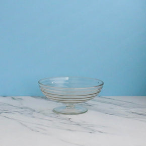 Clear glass bowl on a marble surface with a light blue background