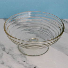 Clear glass bowl on a marble surface with a blue background
