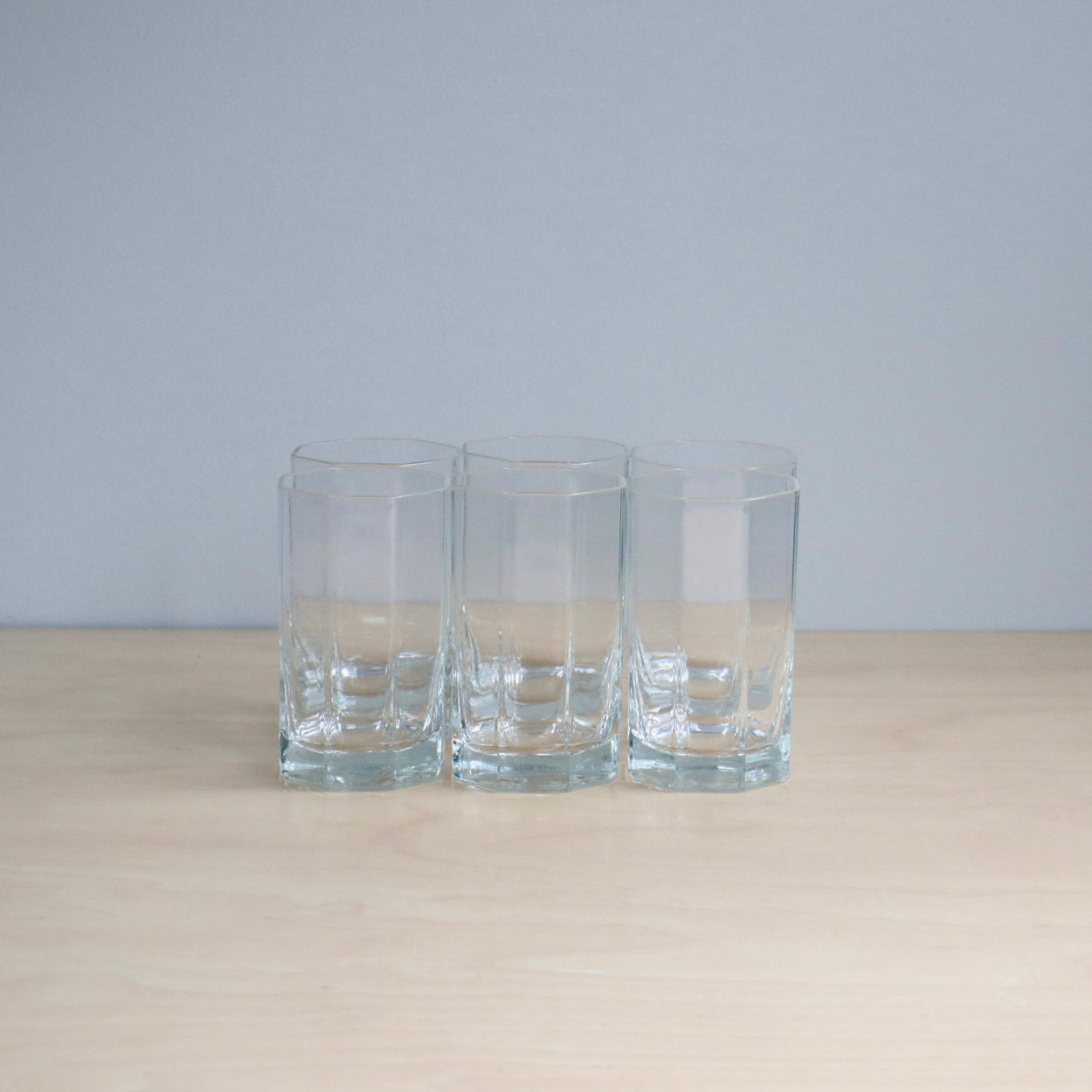 Three clear glass tumblers on a light surface with a light gray background
