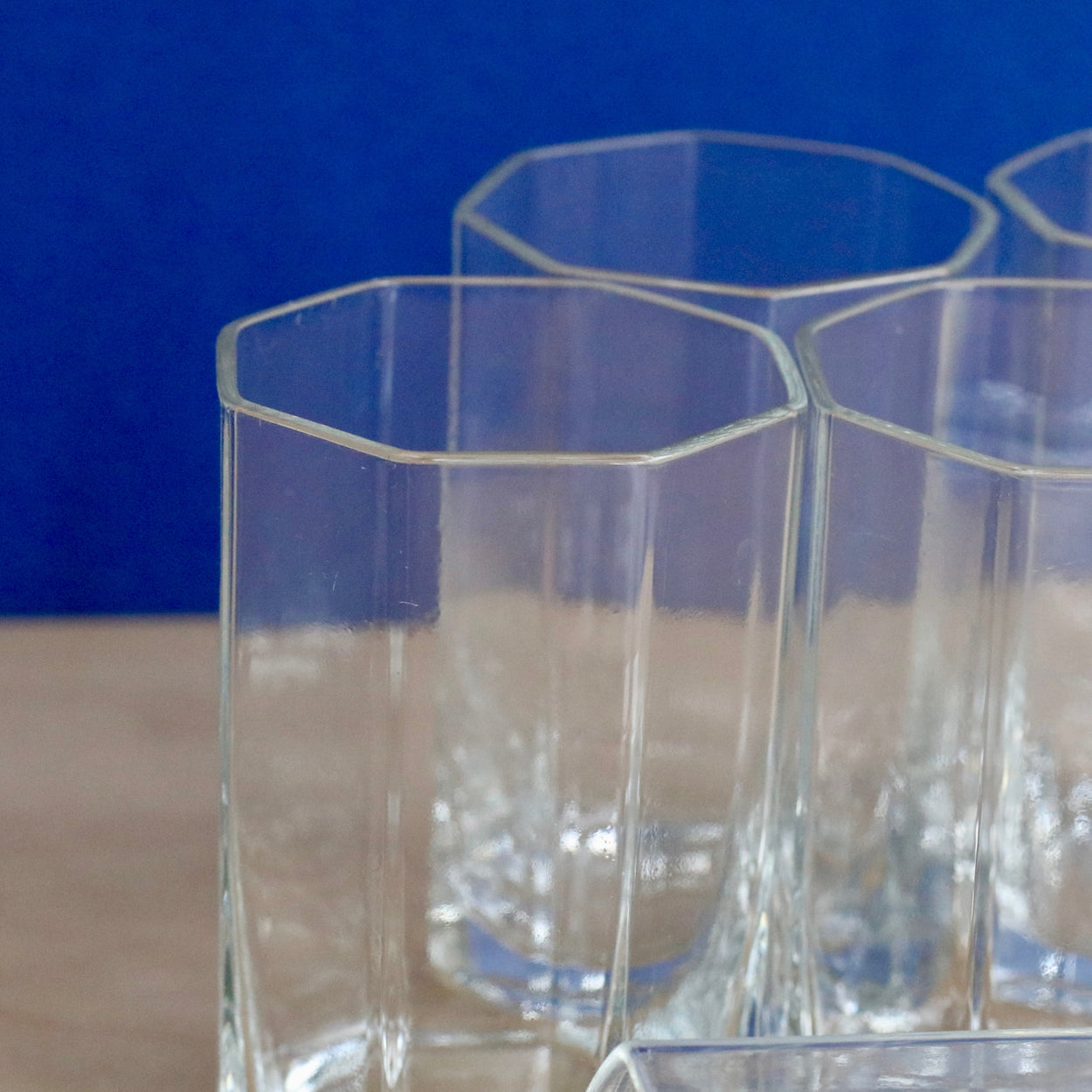 Close up of clear glass geometric tumblers on a blue background