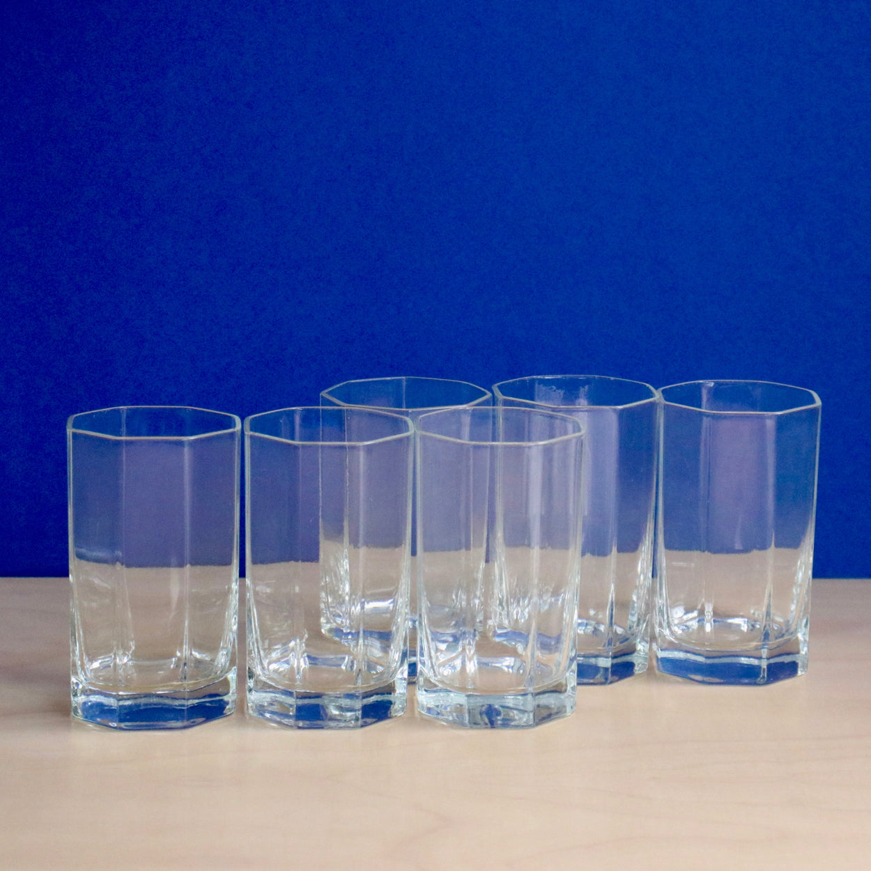 Set of six octagonal glasses against a blue backdrop.