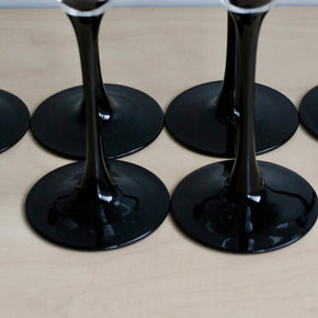 Close up of set of black wine glass bases on a beige surface