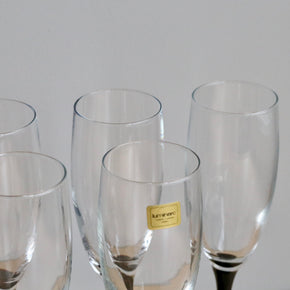 Set of clear glasses with a brand label on a light gray background