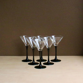 Set of six black-stemmed martini glasses on a beige surface with a brown background