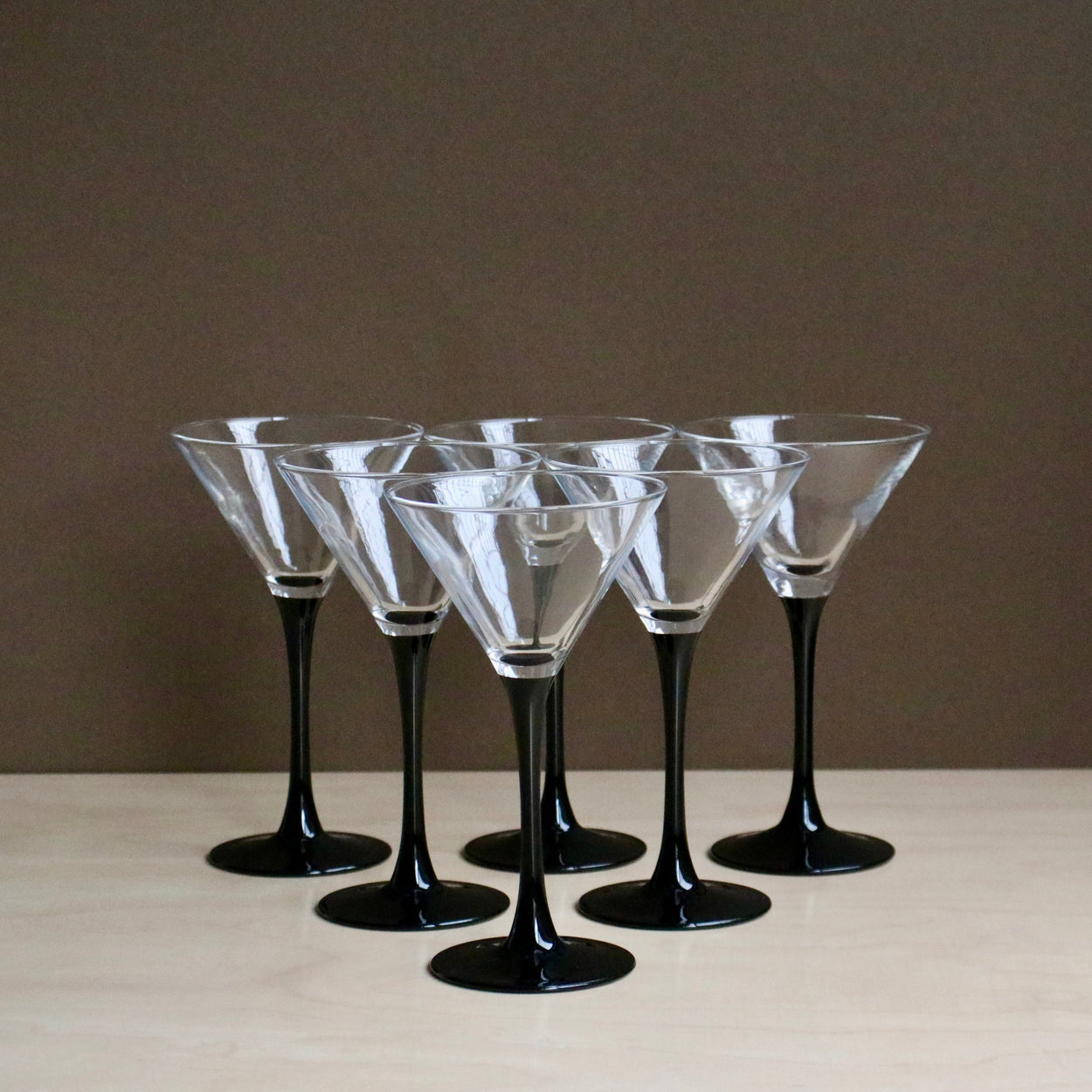 Set of six martini glasses with black stems on a neutral background