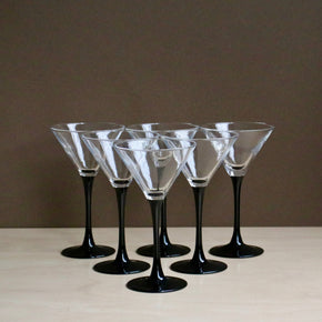 Set of six martini glasses with black stems on a neutral background