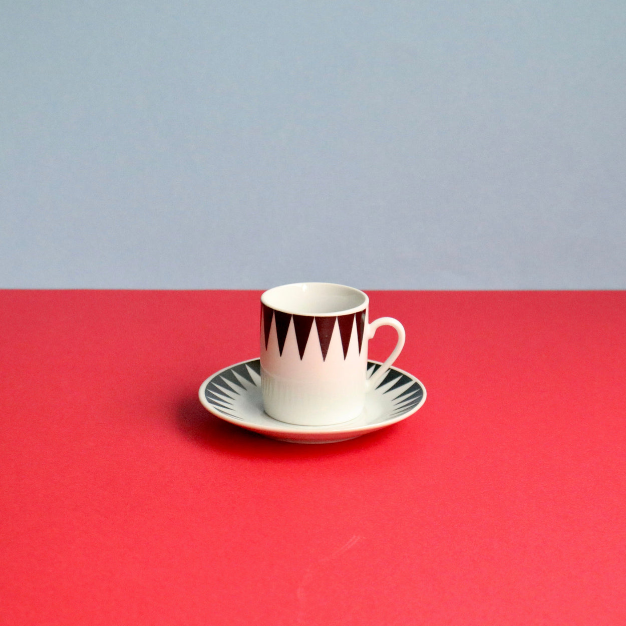 Ceramic cup with a saucer on a red and gray background