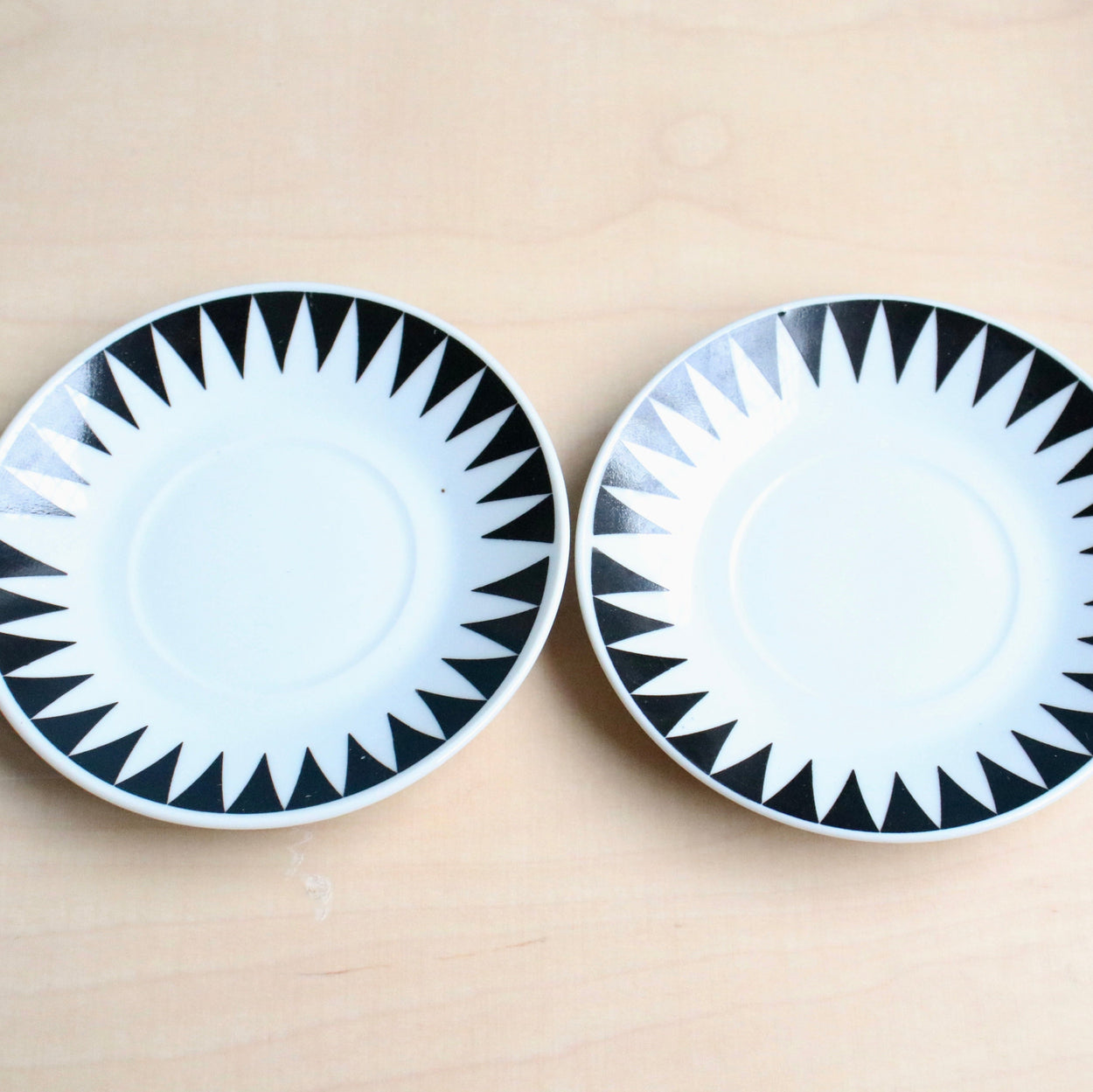 Two black and white patterned saucers on a beige surface