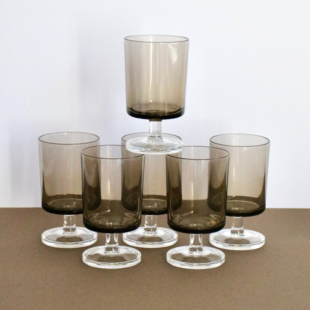 Set of six smoked glass tumblers on a neutral background