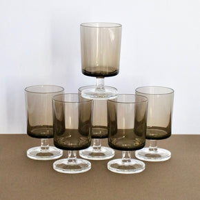 Set of six smoked glass tumblers on a neutral background