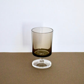 Smoky glass tumbler on a brown surface with a white background