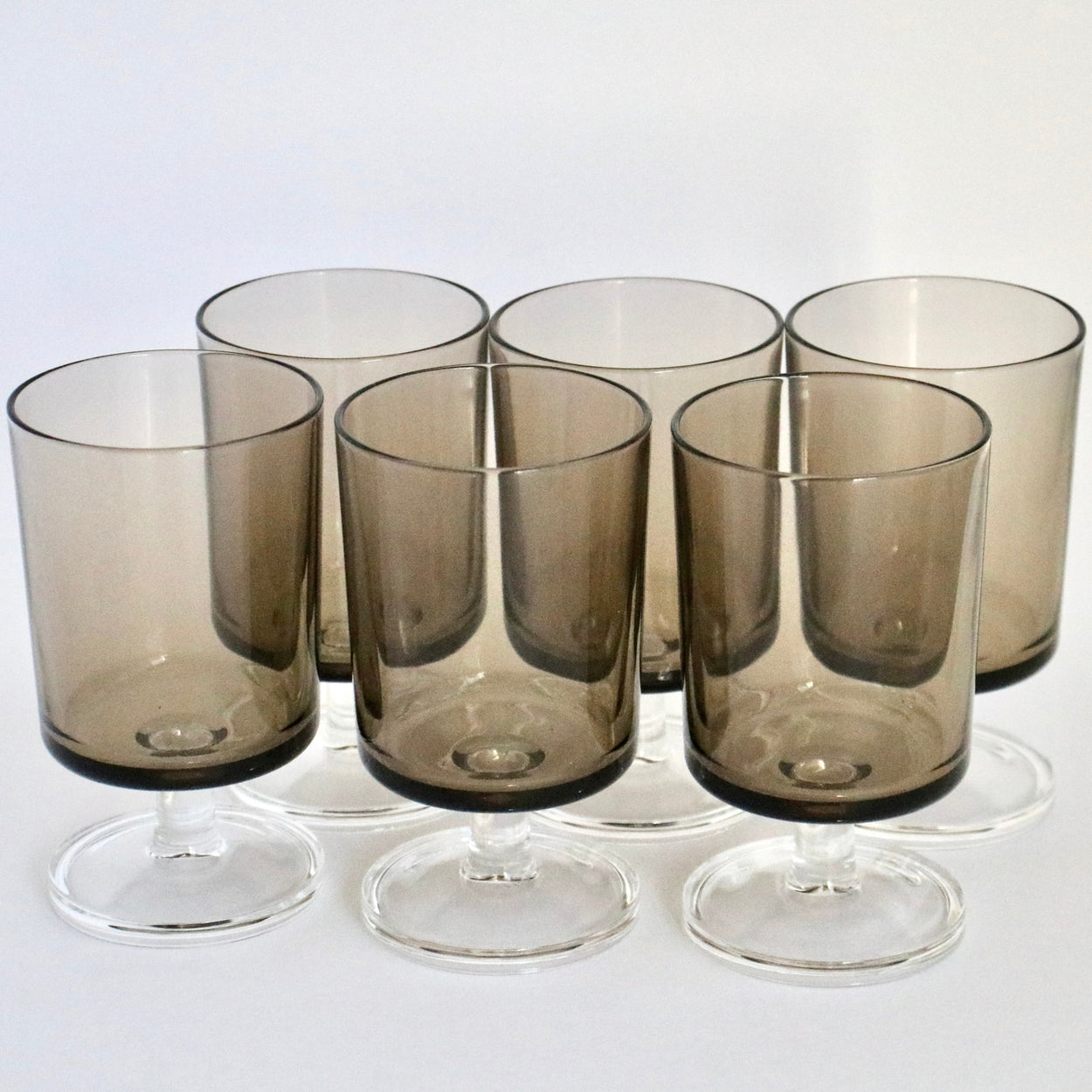 Set of six smoked glass tumblers on a white background