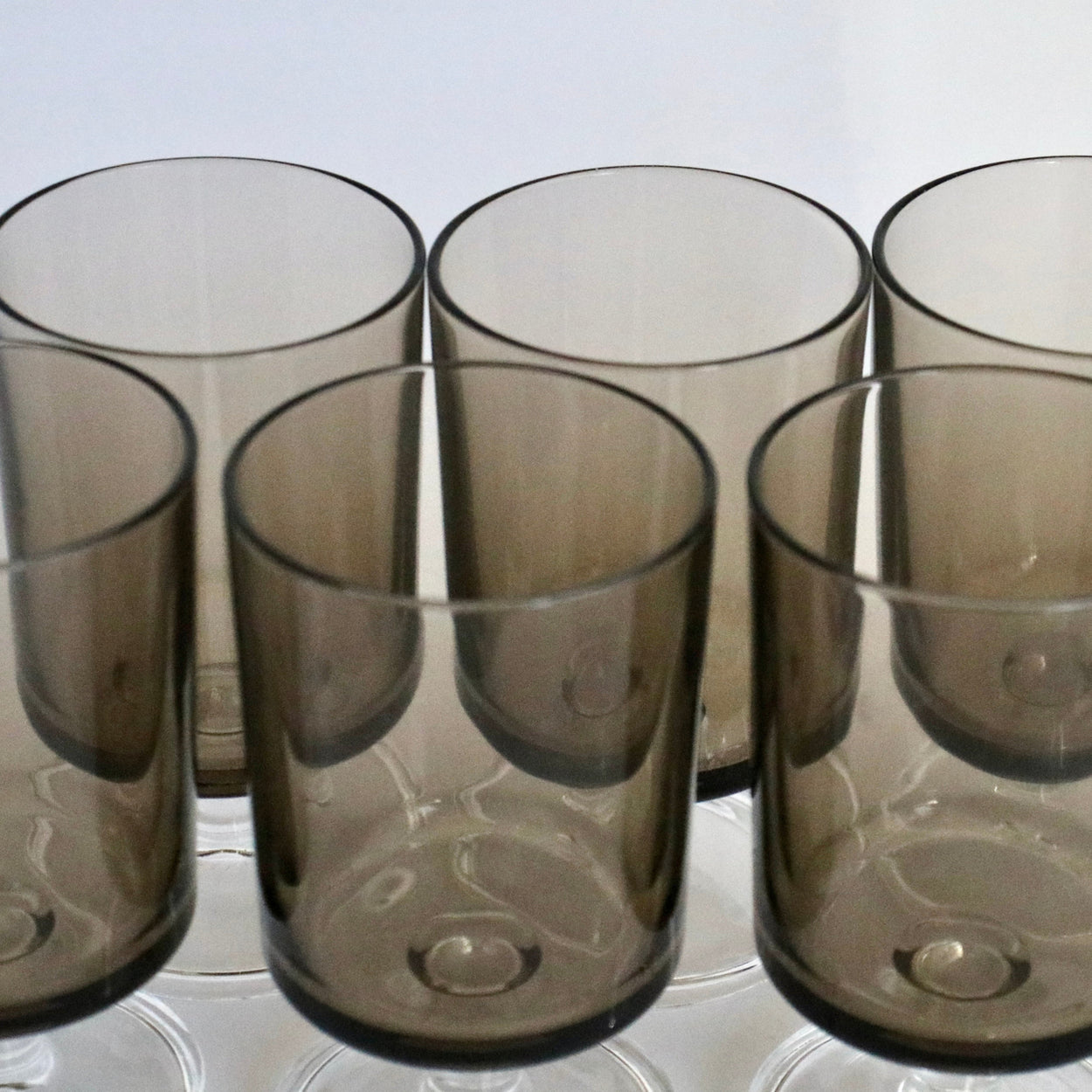 Set of six smoked glass tumblers on a white surface