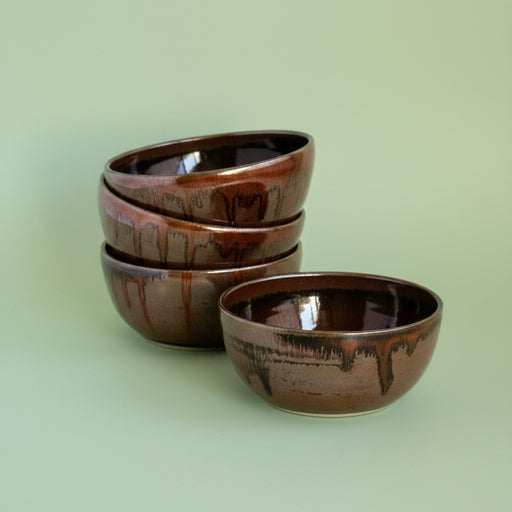 Set of four brown ceramic bowls on a green background