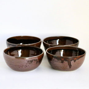 Four brown ceramic bowls on a white background
