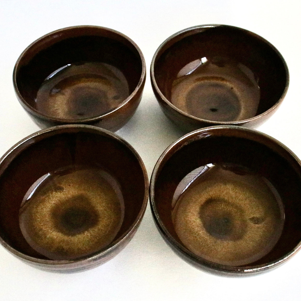 Four brown ceramic bowls on a white background