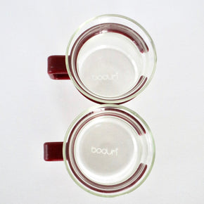 Two glass mugs with red handles on a white background