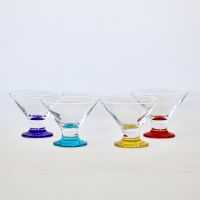 Four martini glasses with colored bases on a white background