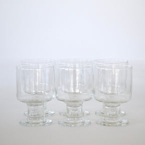 Six clear glass goblets on a white background