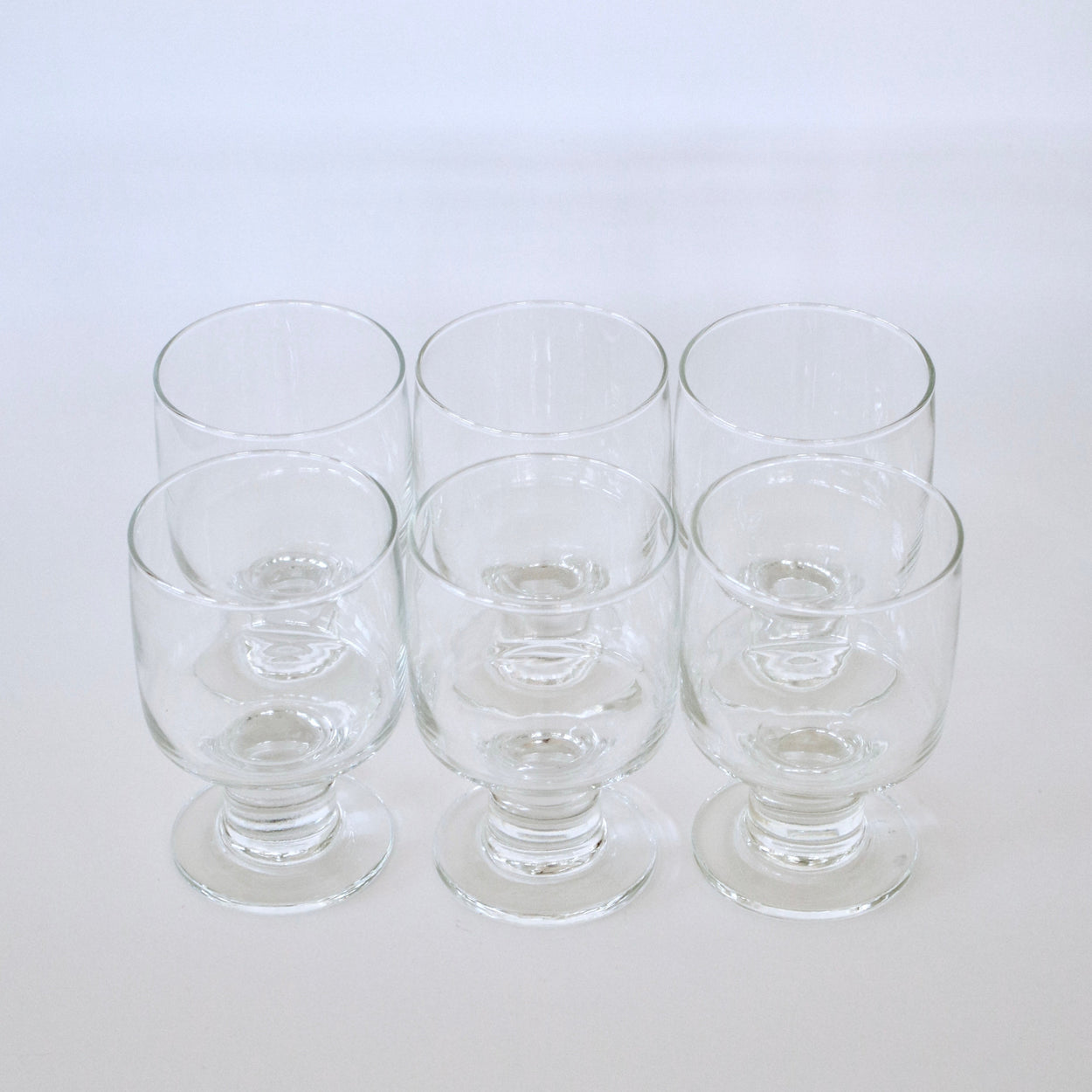 Set of six clear glass tumblers on a white background