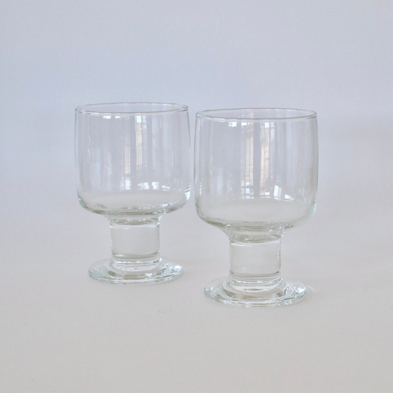 Two clear glass goblets on a light gray background