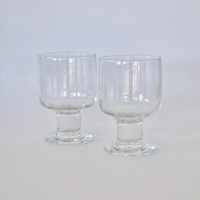 Two clear glass goblets on a light gray background
