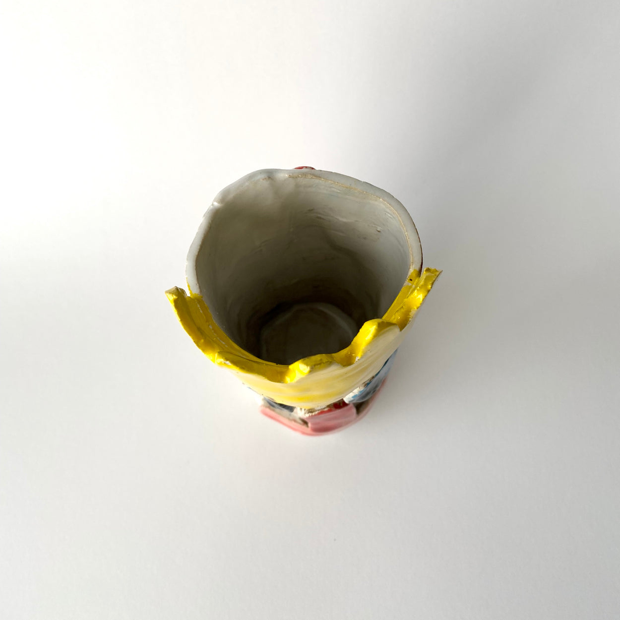 Interior of Ceramic vase with colourful face design on a light grey background