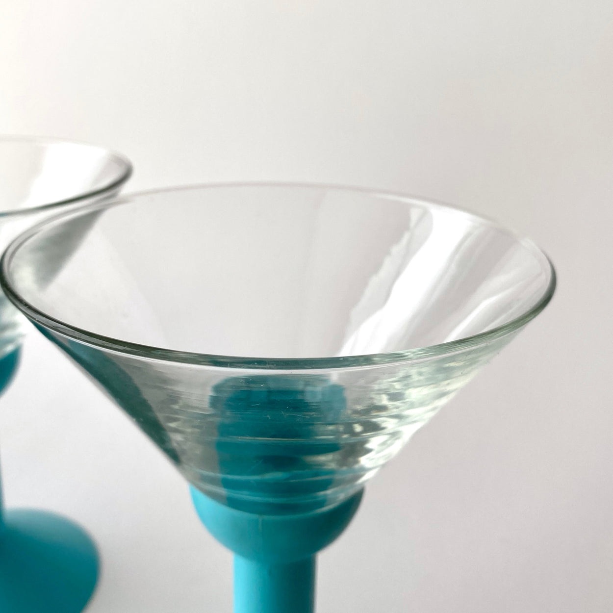 Clear glass cocktail glass with blue base on a white background