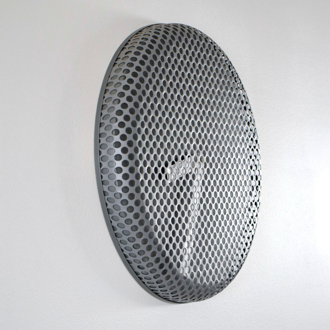 Round metallic clock with honeycomb face on a white background