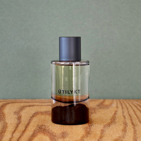 Clear perfume bottle with a dark cap on a wooden surface and gray background