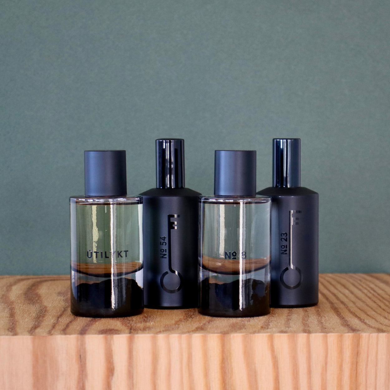 Four perfume bottles on a wooden surface with a plain background