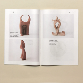 Open book showing ceramic sculptures on a beige background