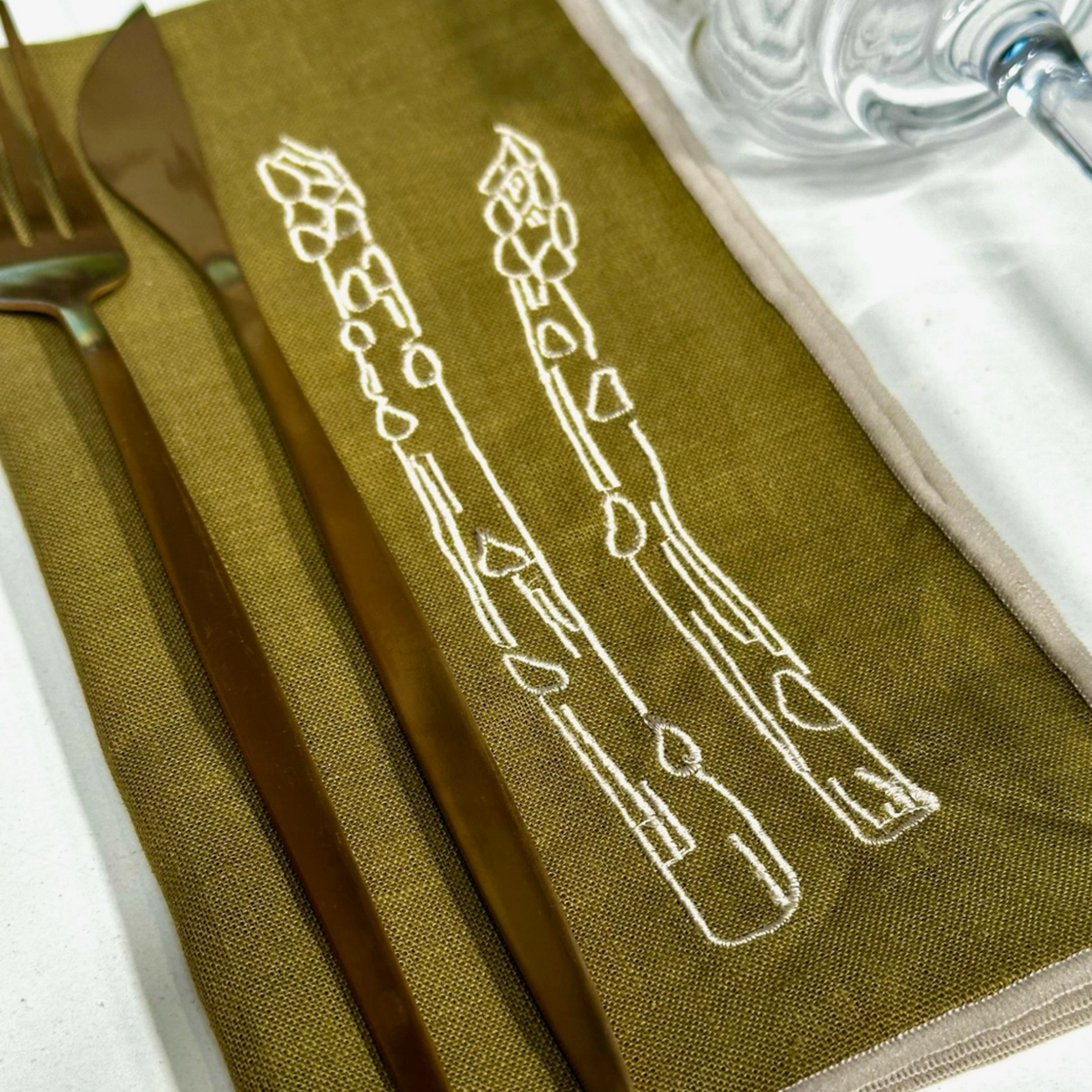Green napkin with white asparagus illustration on a table setting.