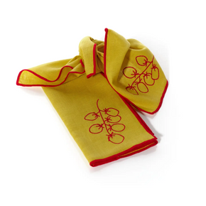 Yellow napkin with red trim and embroidery on a white background