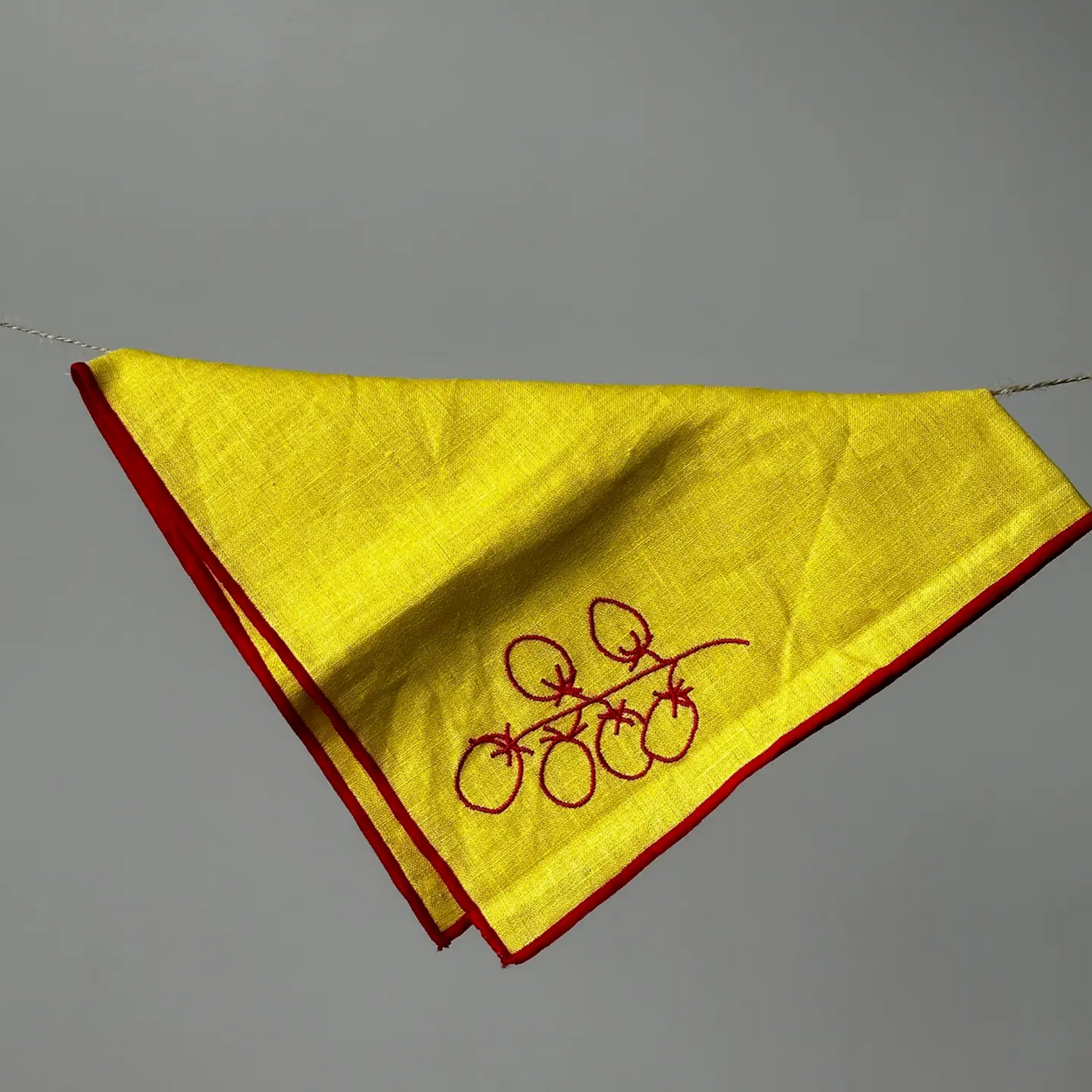 Yellow napkin with red border and embroidery on a gray background