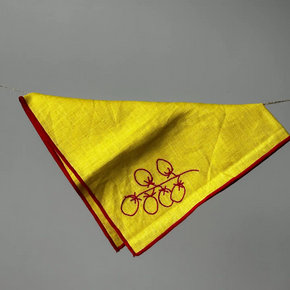 Yellow napkin with red border and embroidery on a gray background