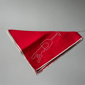 A red napkin banner with white embroidered wine glass outlines, strung along a thin cord against a plain gray background.