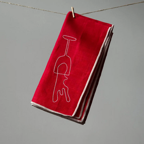 Red napkin with a white wine glass outline hanging on a line against a gray background