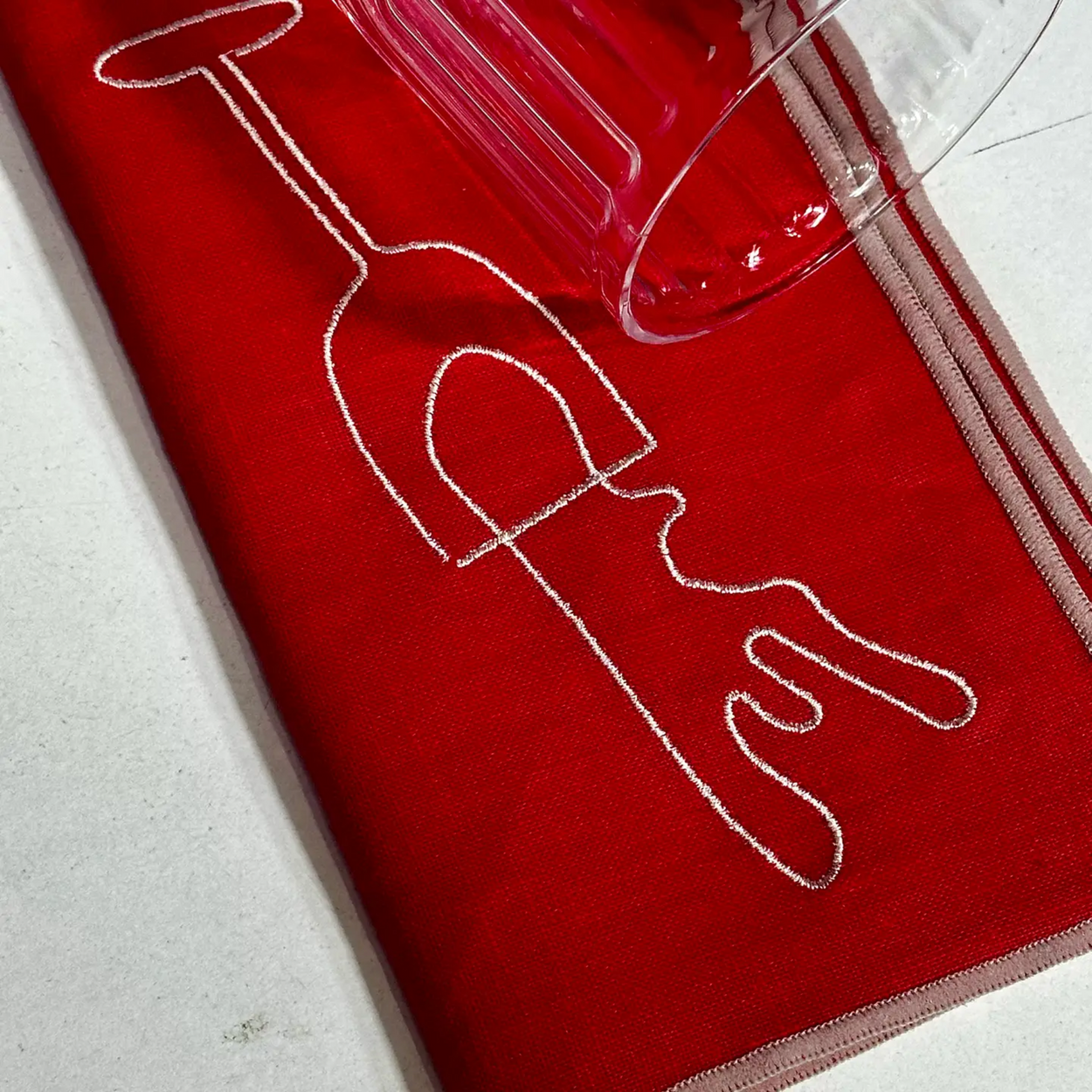 Red napkin with white line art of a glass on a light gray background