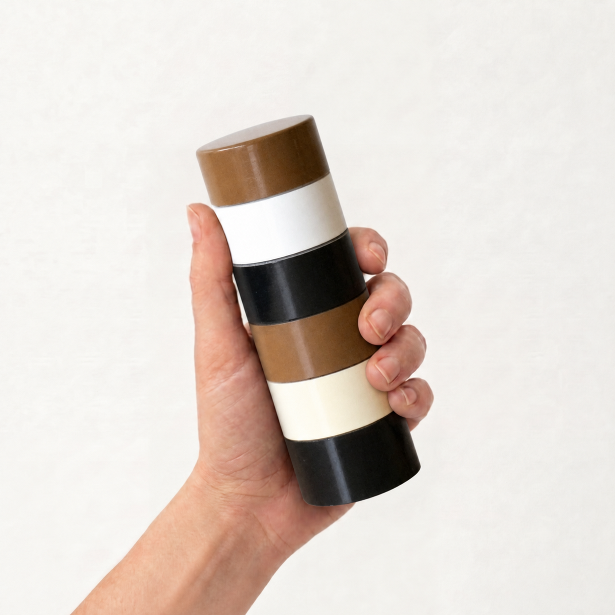 Hand holding Brown striped Semi-D salt and pepper grinder.