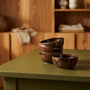 Three brown ceramic bowls on a green table with a wooden background