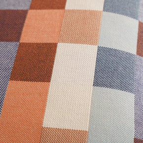 Close-up of Mungo Wild Fire double cotton checkered fabric cushion with brown, blue, and beige squares.