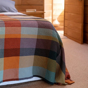 Mungo Vrou-Vrou cotton Waffle Blanket - Cypress on bed in wood lined room.