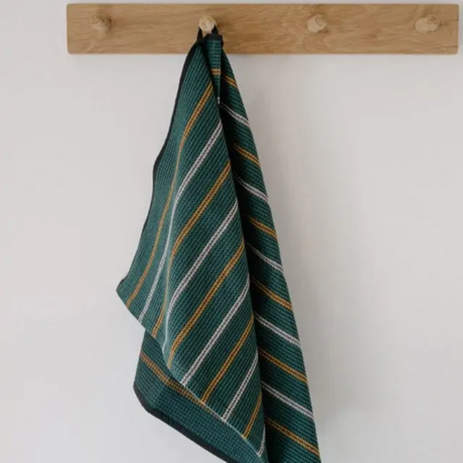 Mungo Waffle Tea Towel in Juniper green hanging on wood hooks.