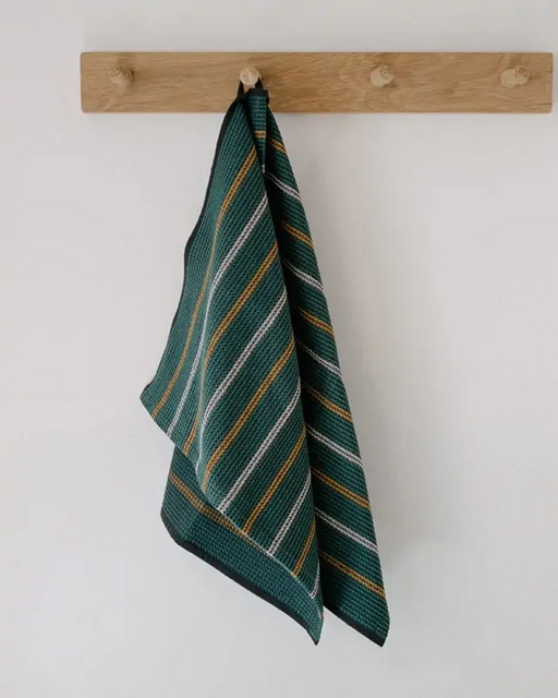 Mungo Waffle Tea Towel in Juniper green hanging on wood hooks.