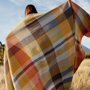 Woman in field holding Mungo Vrou-Vrou Cotton Waffle Blanket - Tamarind across her shoulders.